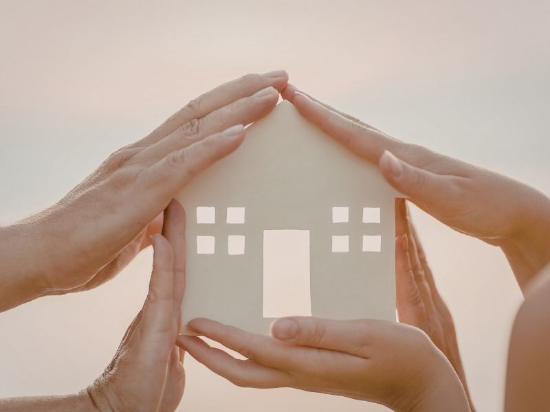 Maison avec des mains dessus pour suggérer la protection du couple dans le domicile